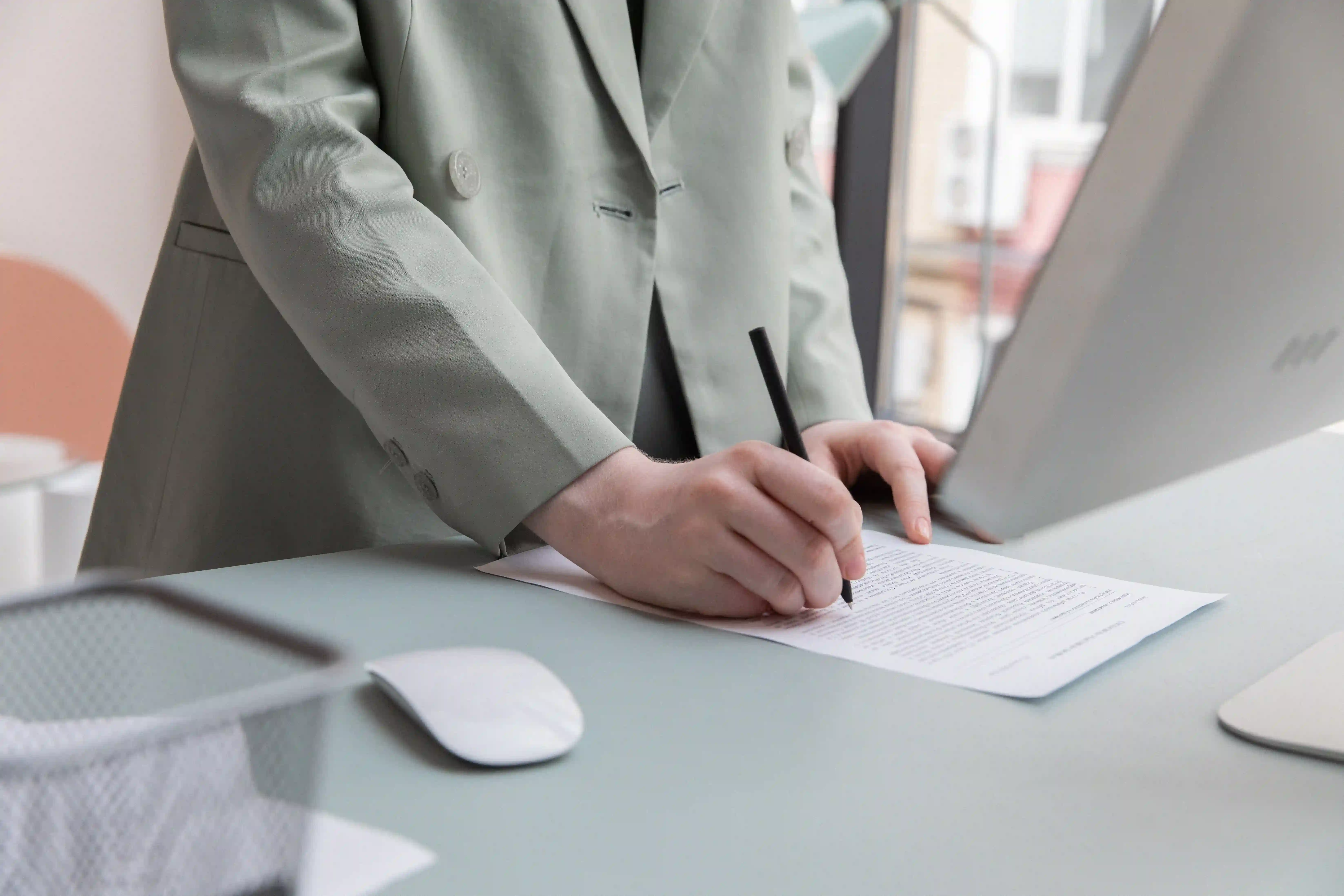 picture of a person standing at a desk writing on document
