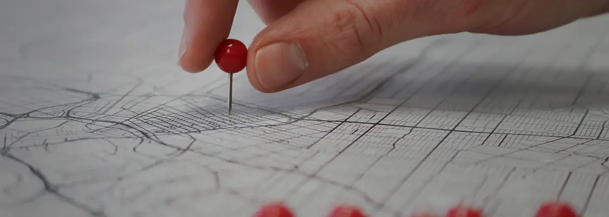 photo of a hand putting a pin into a map of a city