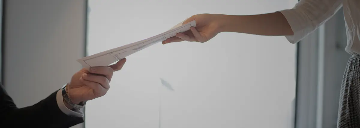 picture of one person handing documents to another person