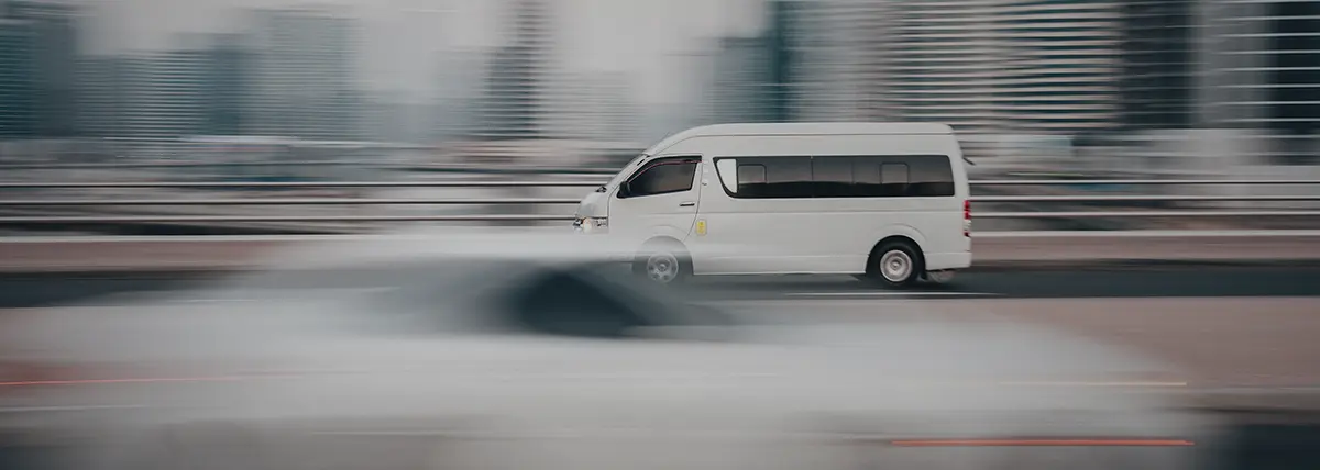 picture of a white van speeding along a highway through a city